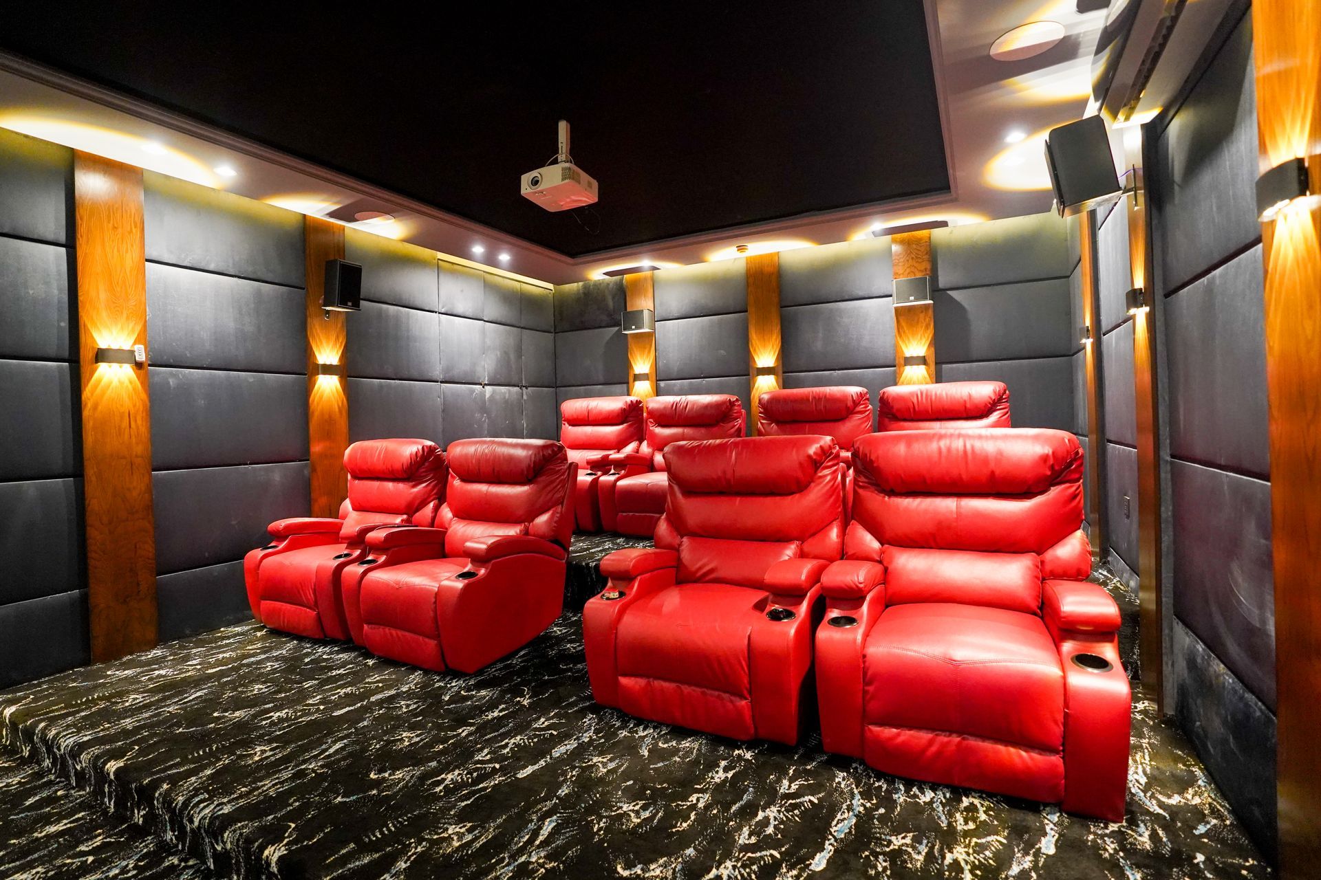 A home theater with red chairs and a projector.