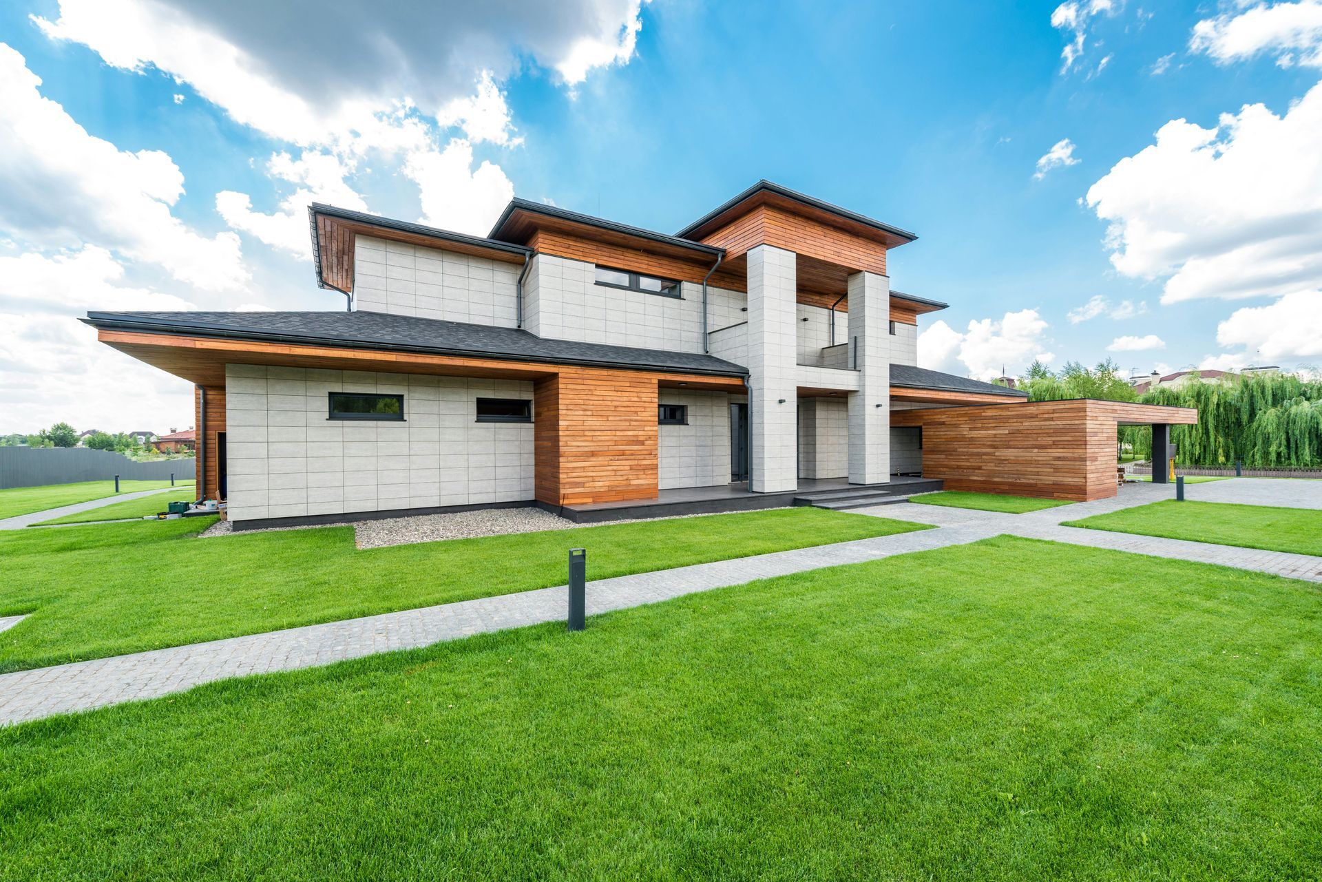 A large modern house with a lush green lawn in front of it.