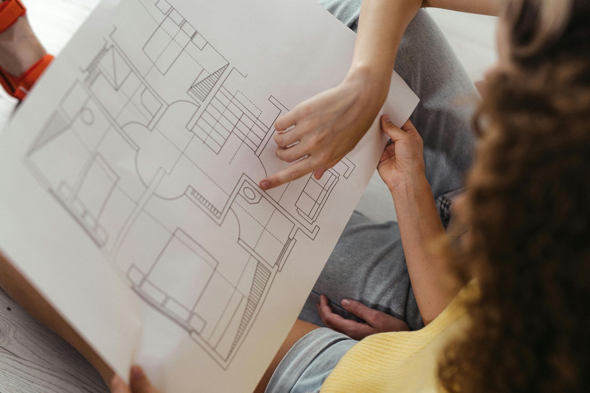 A woman is sitting on the floor looking at a floor plan.