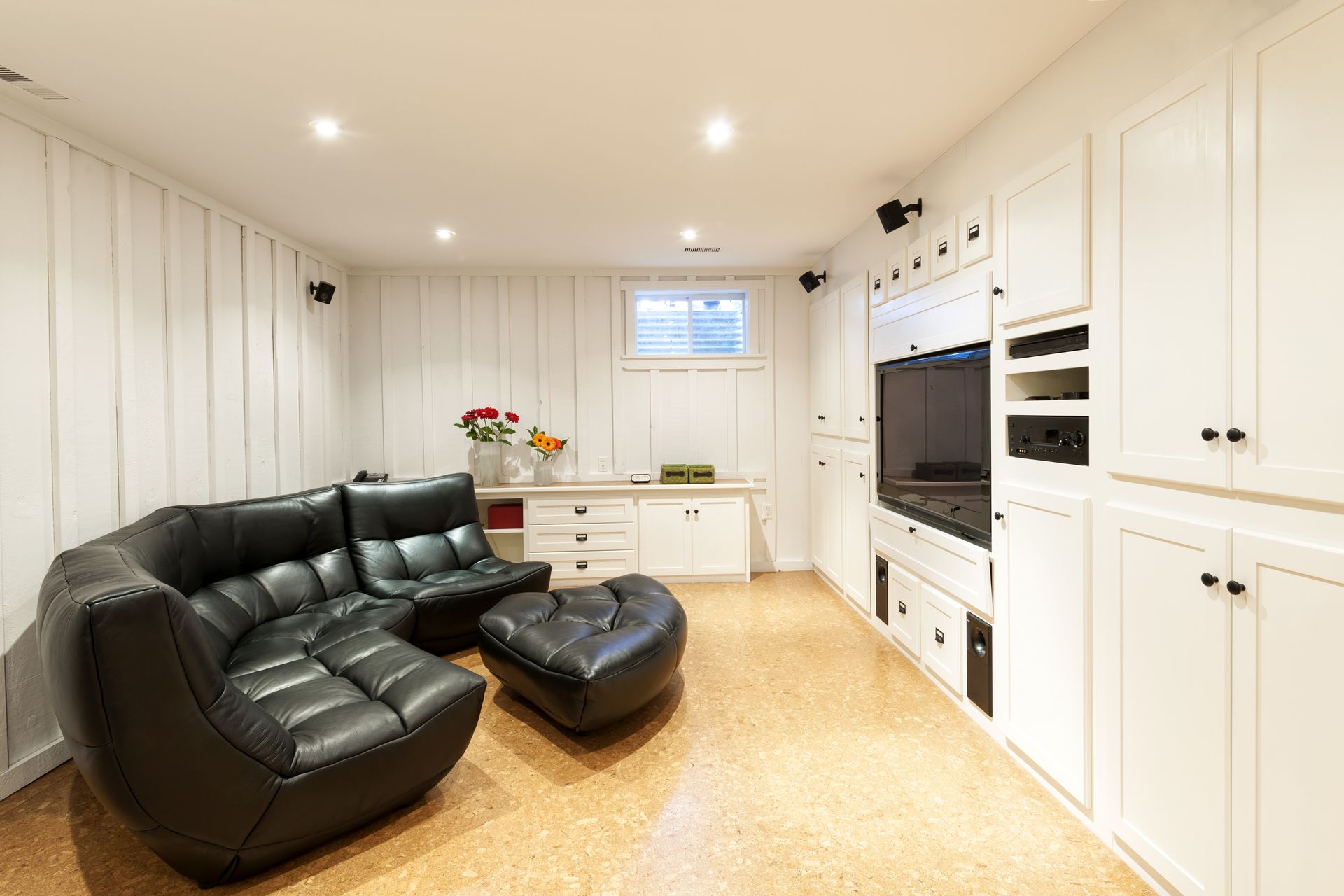 A living room with a couch , chair , ottoman and television.