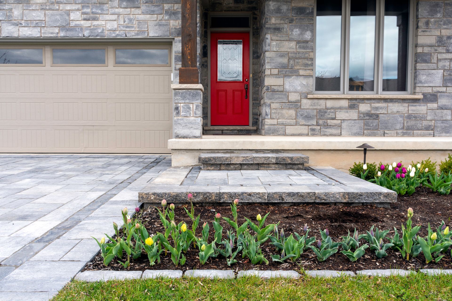 The front of a house with a red door and a walkway leading to it.