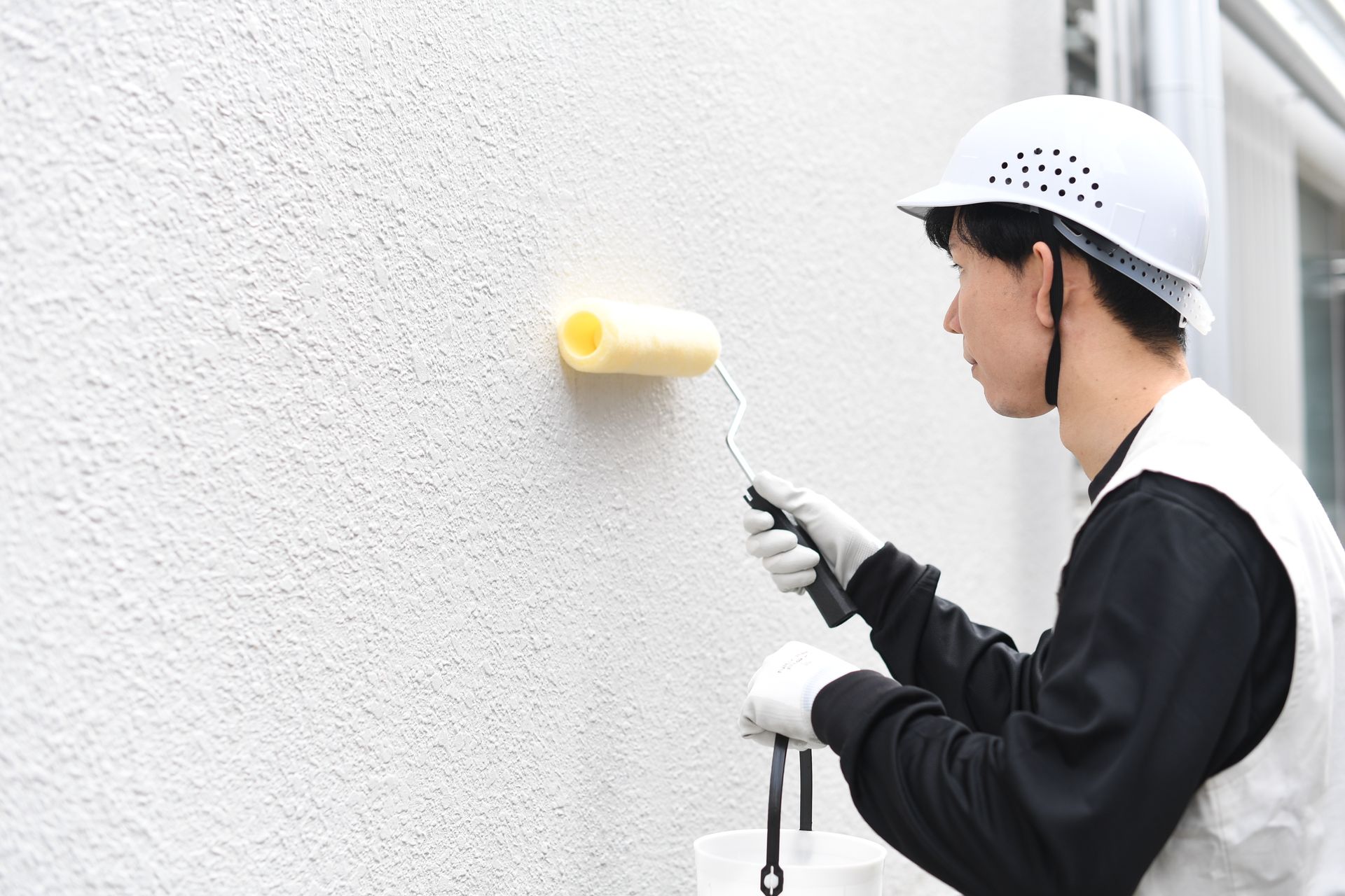 A man is painting a wall with a roller.