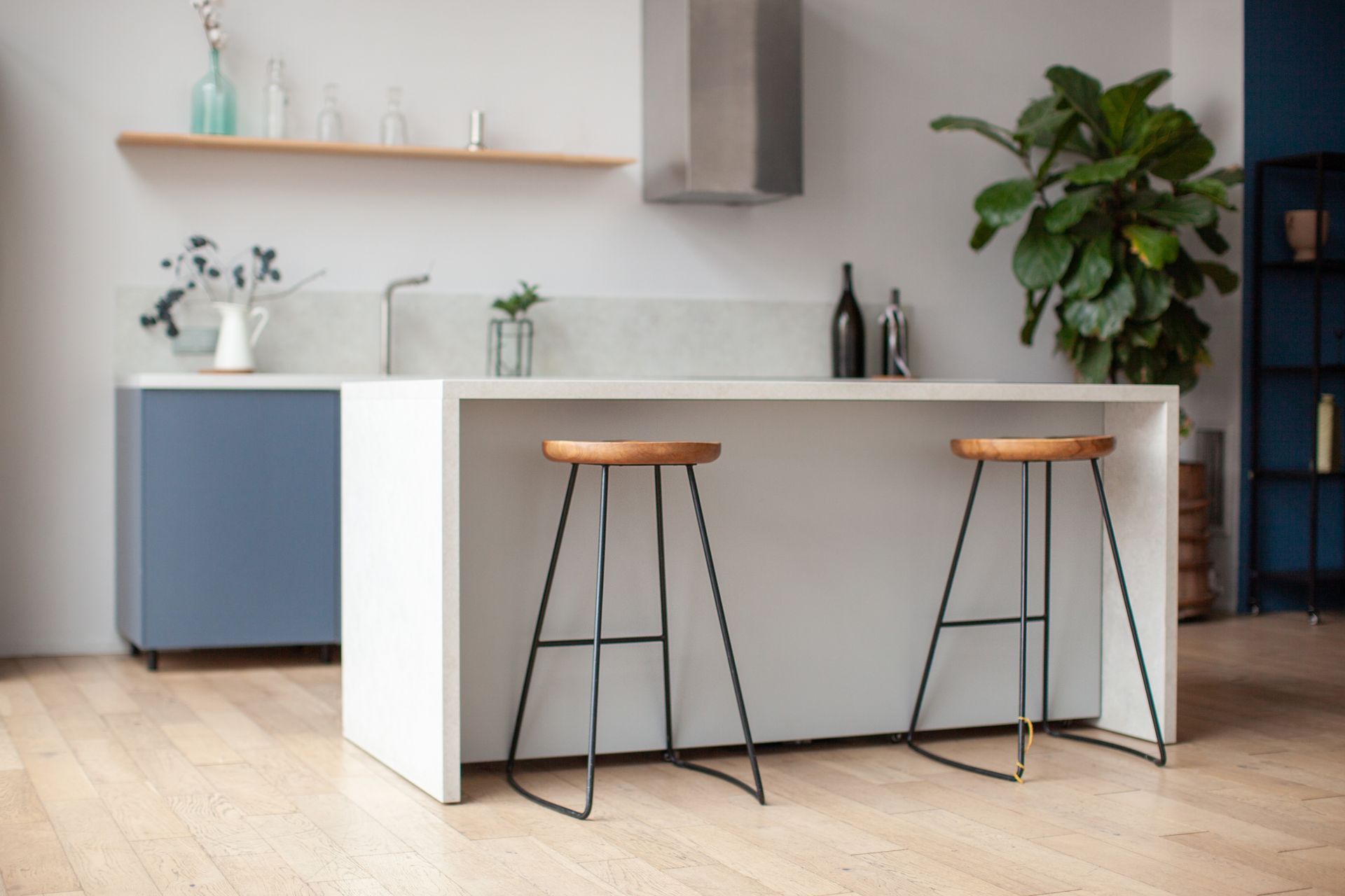 A kitchen with two stools and a plant on the counter.