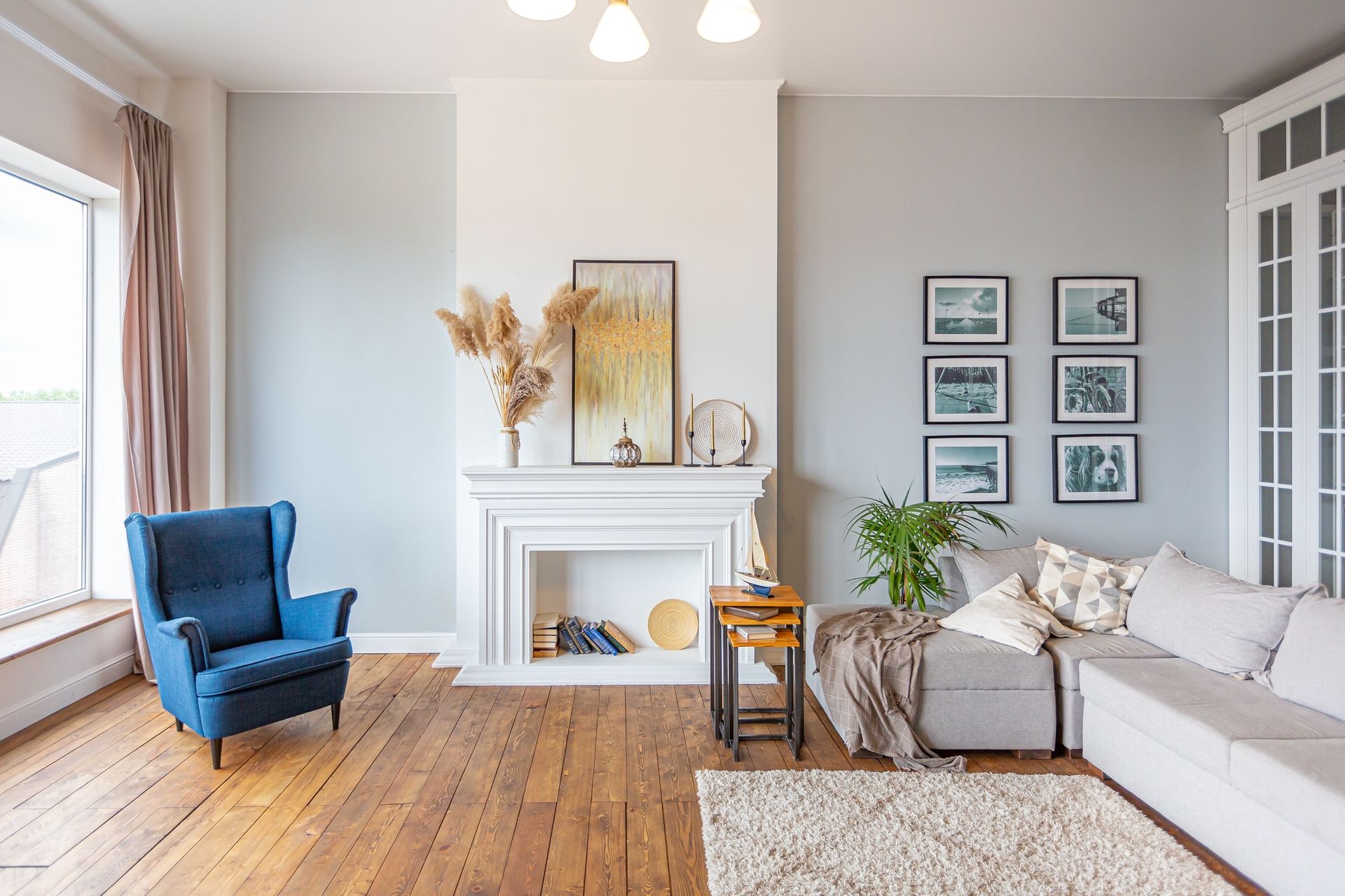 A living room with a couch , chair , fireplace and pictures on the wall.