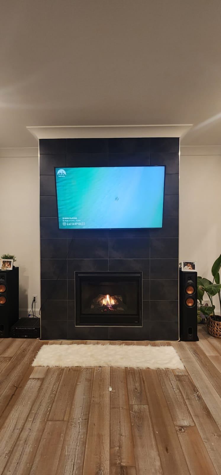 A man and a dog are sitting in front of a fireplace.
