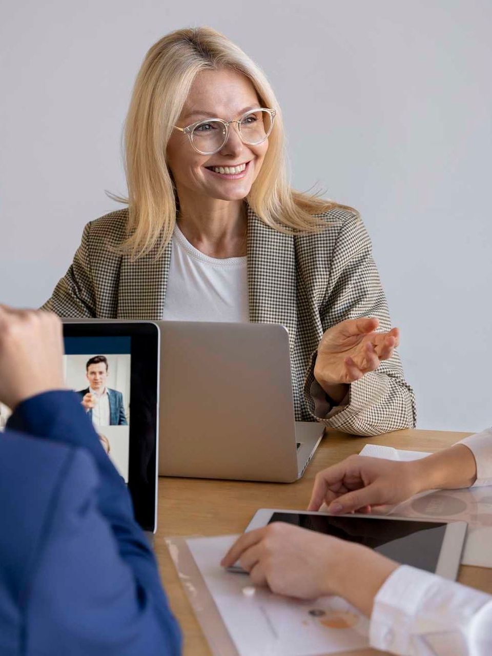 A woman is sitting at a table with a laptop and a tablet.