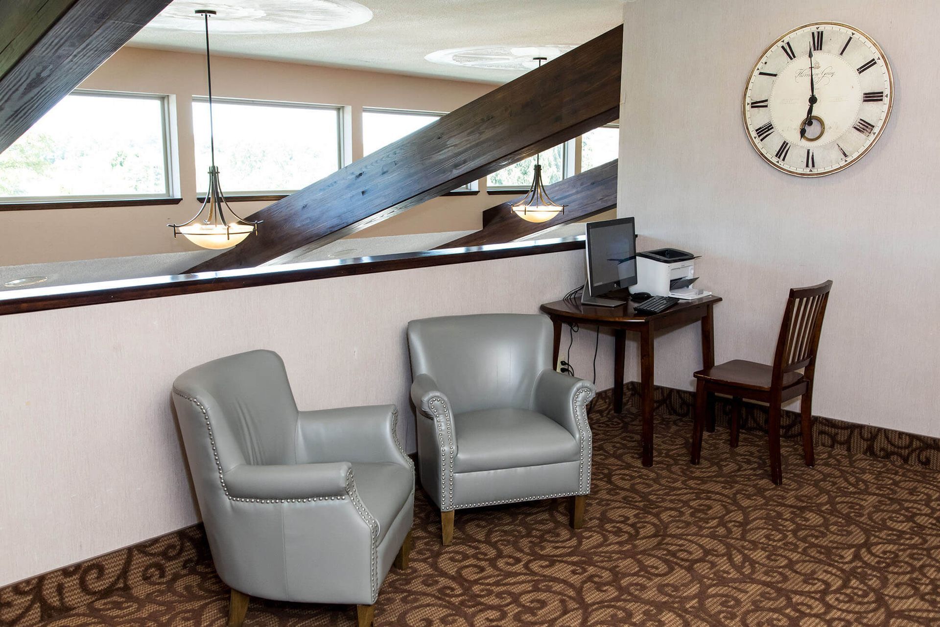 A room with two chairs and a clock on the wall Harvest Inn