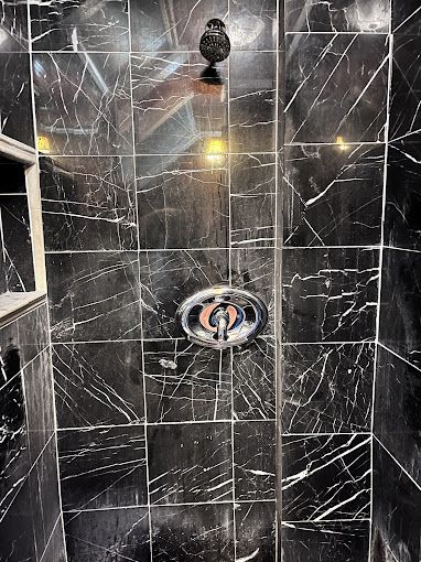 A bathroom with black tiles and a shower head.