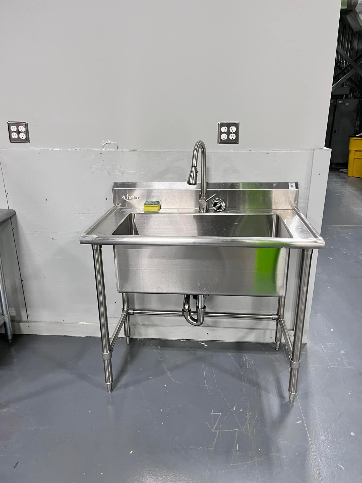 A stainless steel sink with a yellow sponge on it