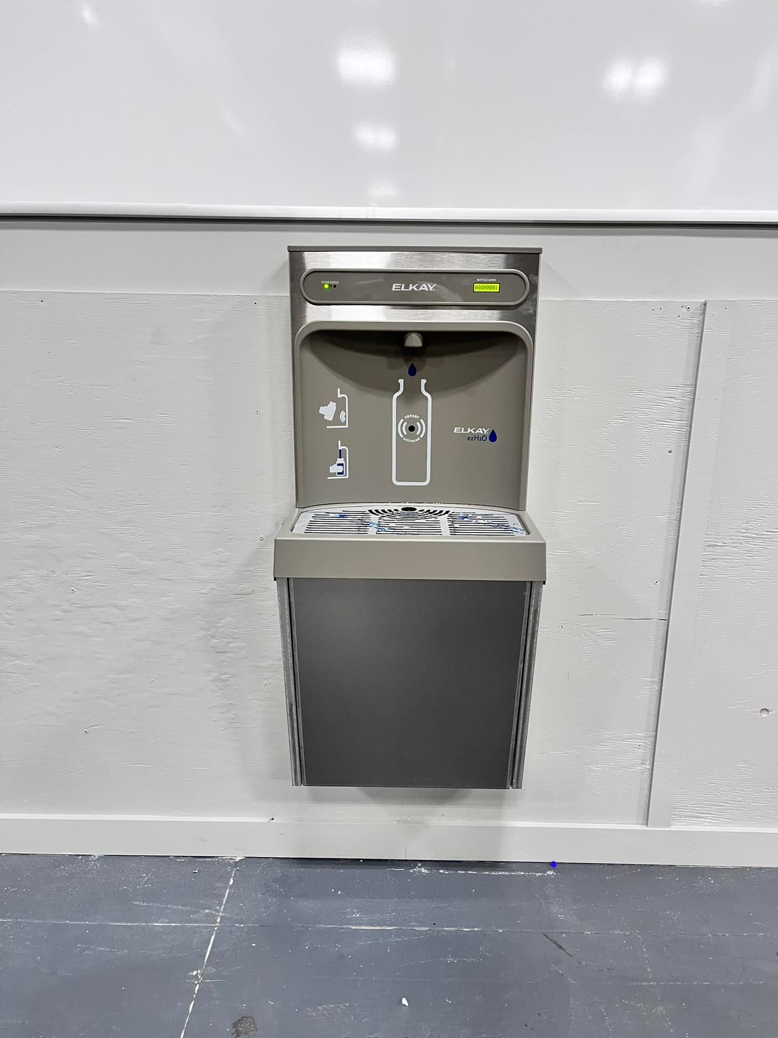 A wall mounted water fountain with a bottle on it