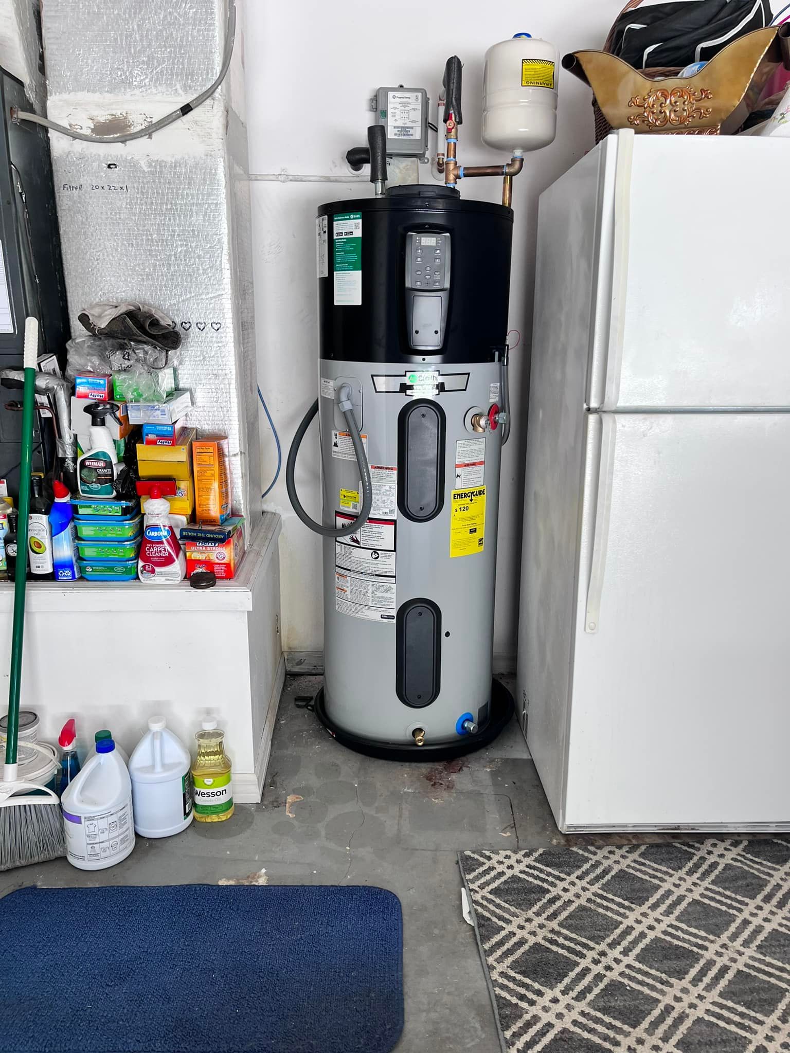 A room with a water heater and a refrigerator