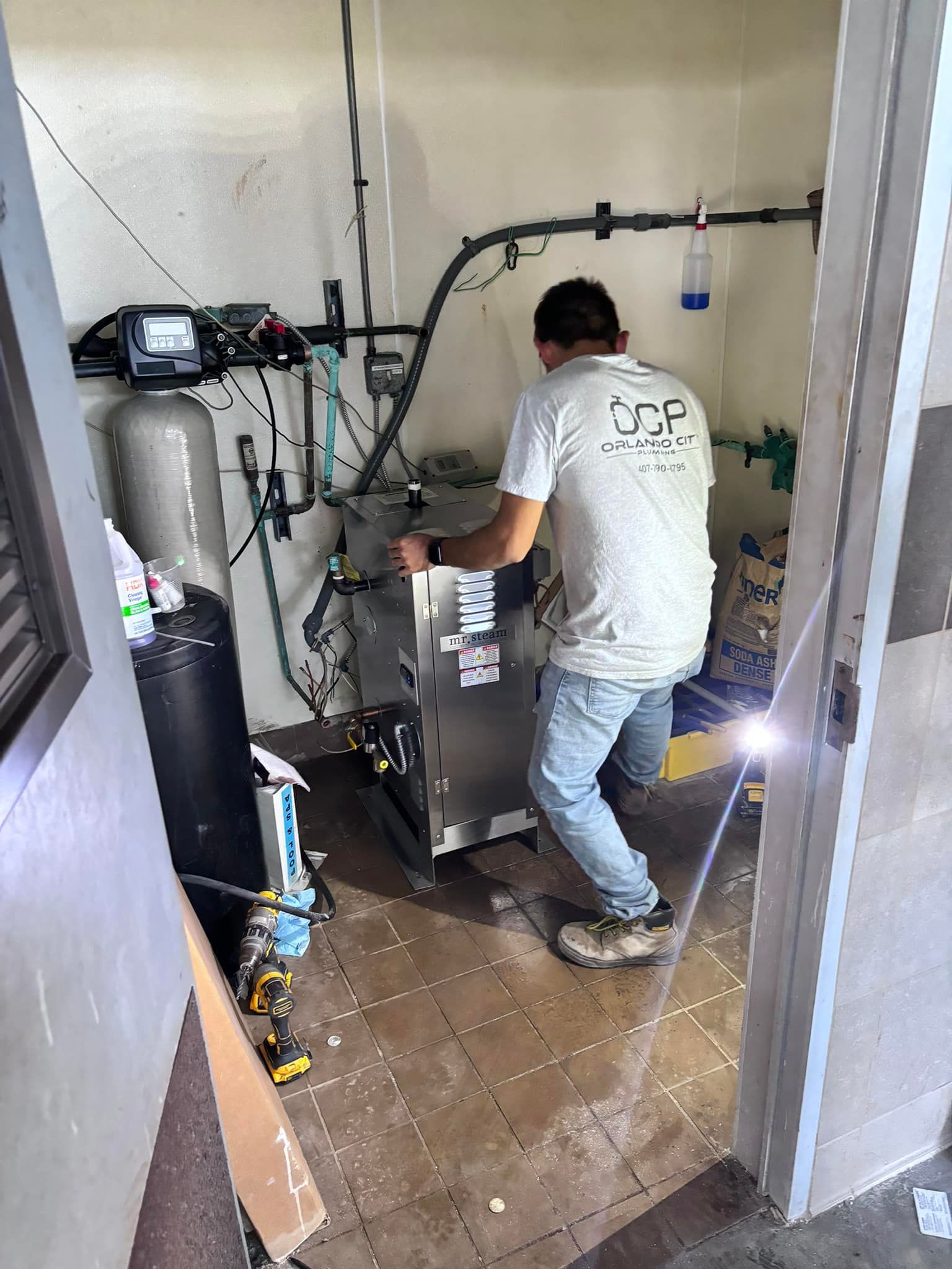 A man wearing a white shirt that says scp on it is working on a machine