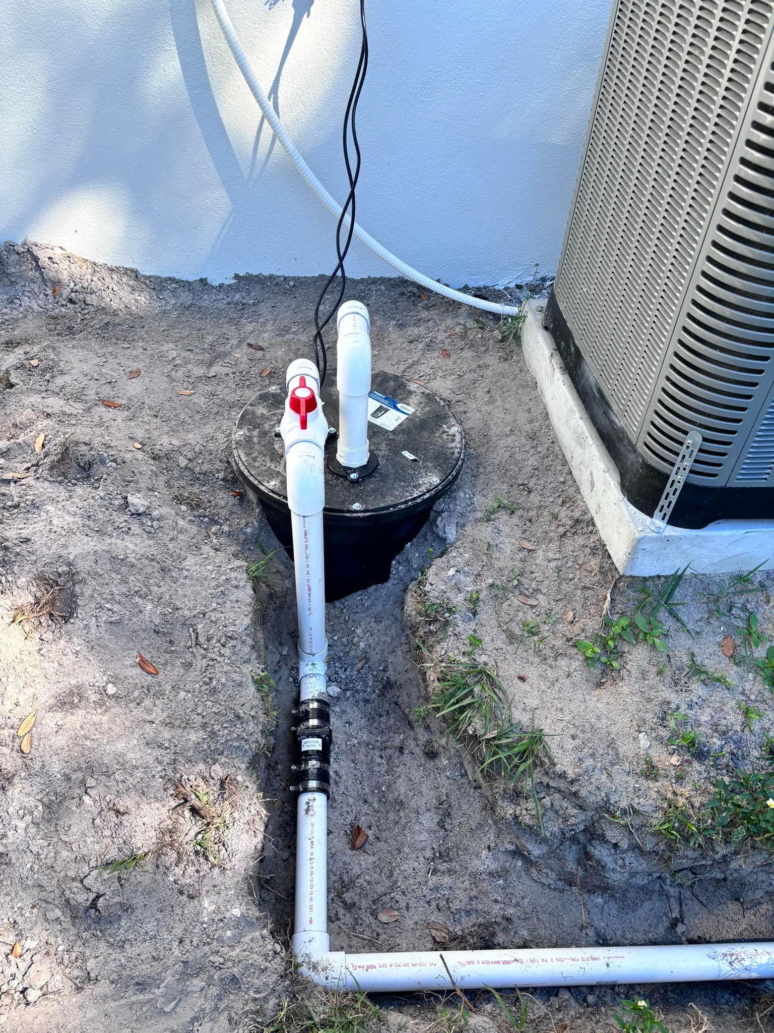 A white pipe with a red valve is connected to an air conditioner