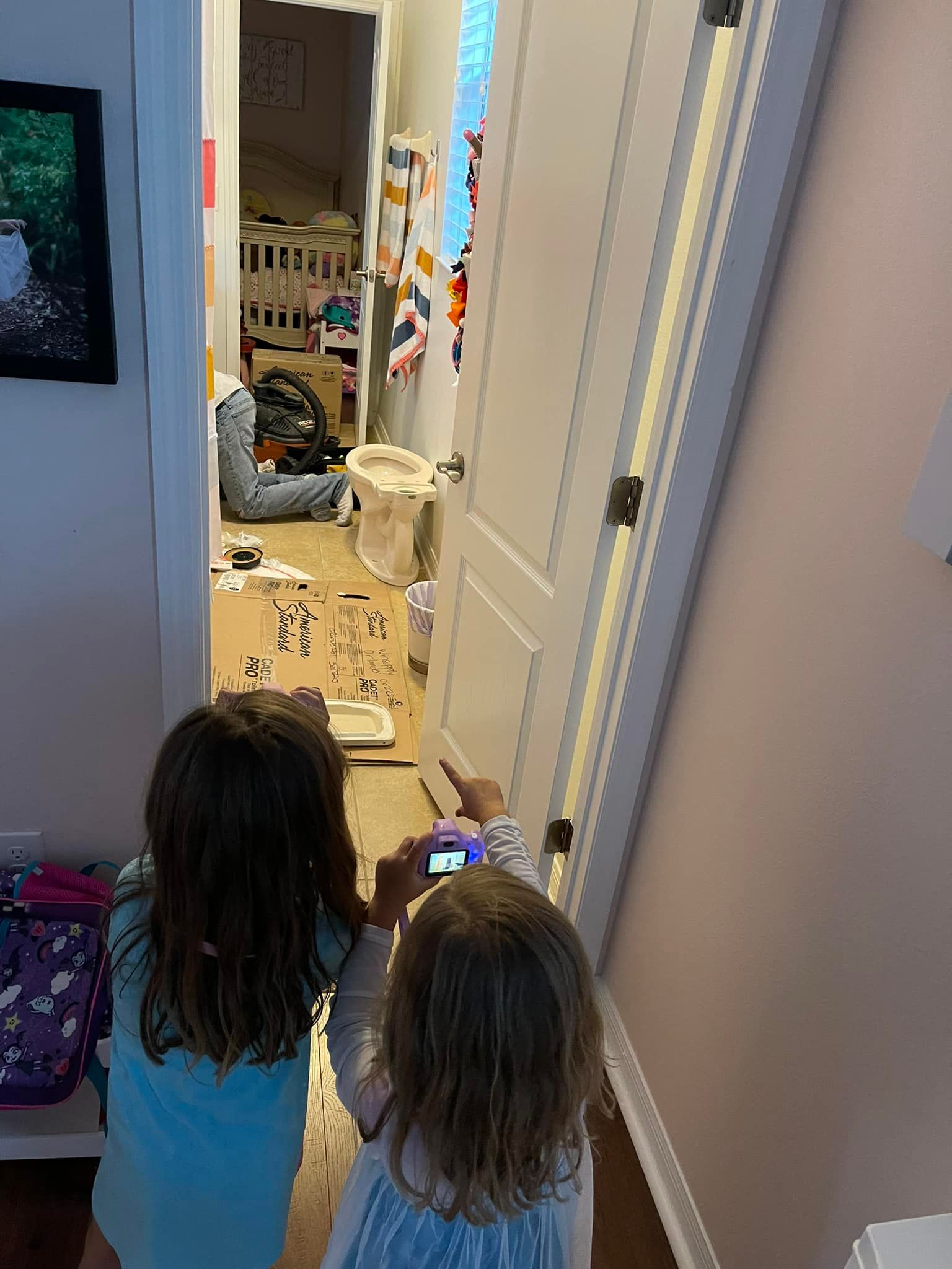 Two little girls looking at a cell phone in a hallway