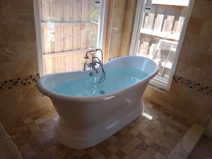 A bathtub in a bathroom next to a window