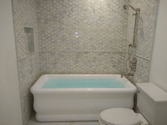 A bathroom with a tub , toilet and shower.