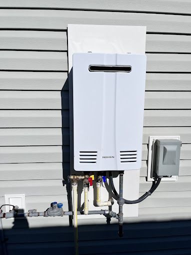 A white water heater is attached to the side of a house.