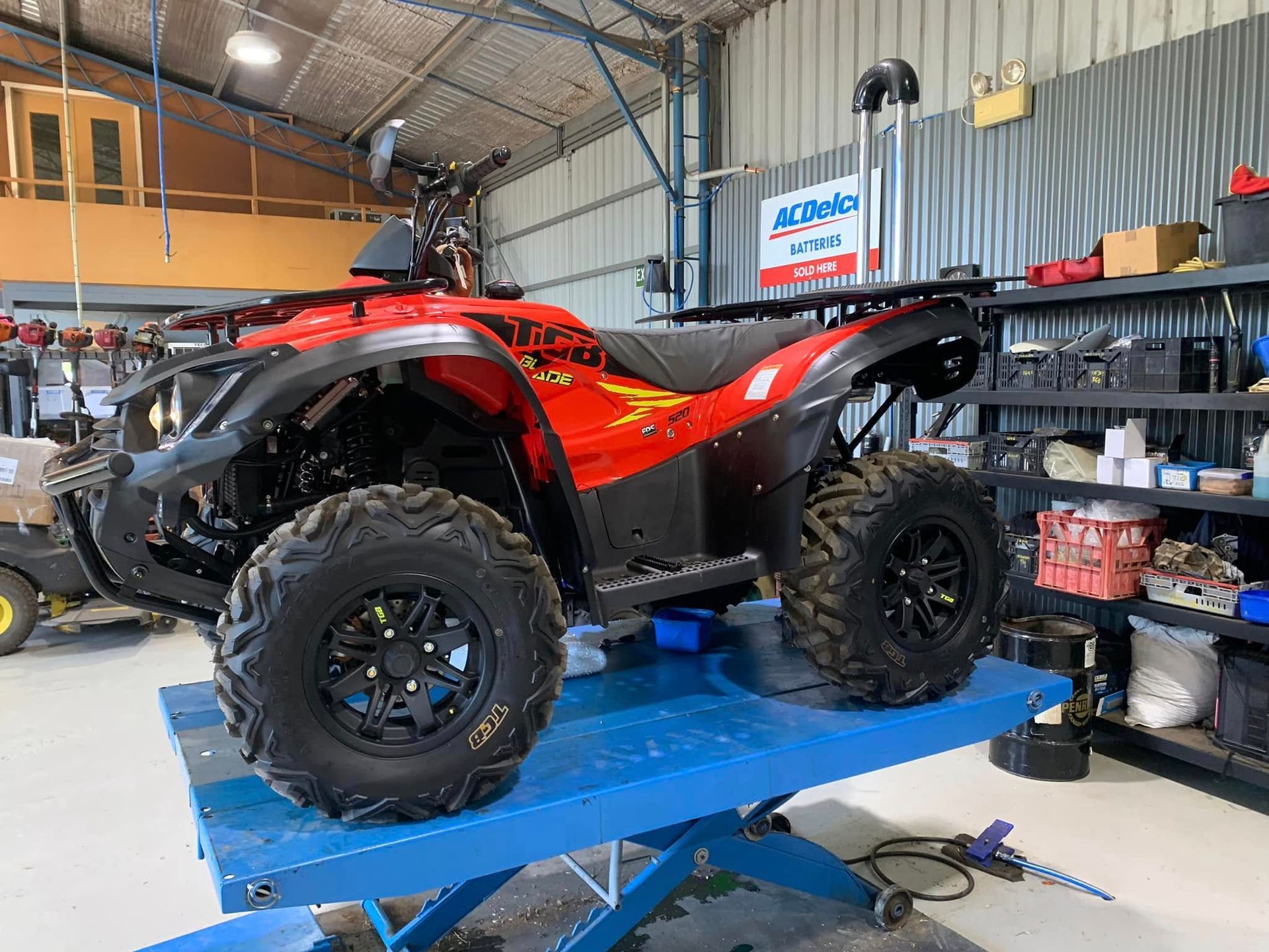 Red and Black ATV on a Blue Lift in a Garage — M.M & Mechanical in Dubbo, NSW