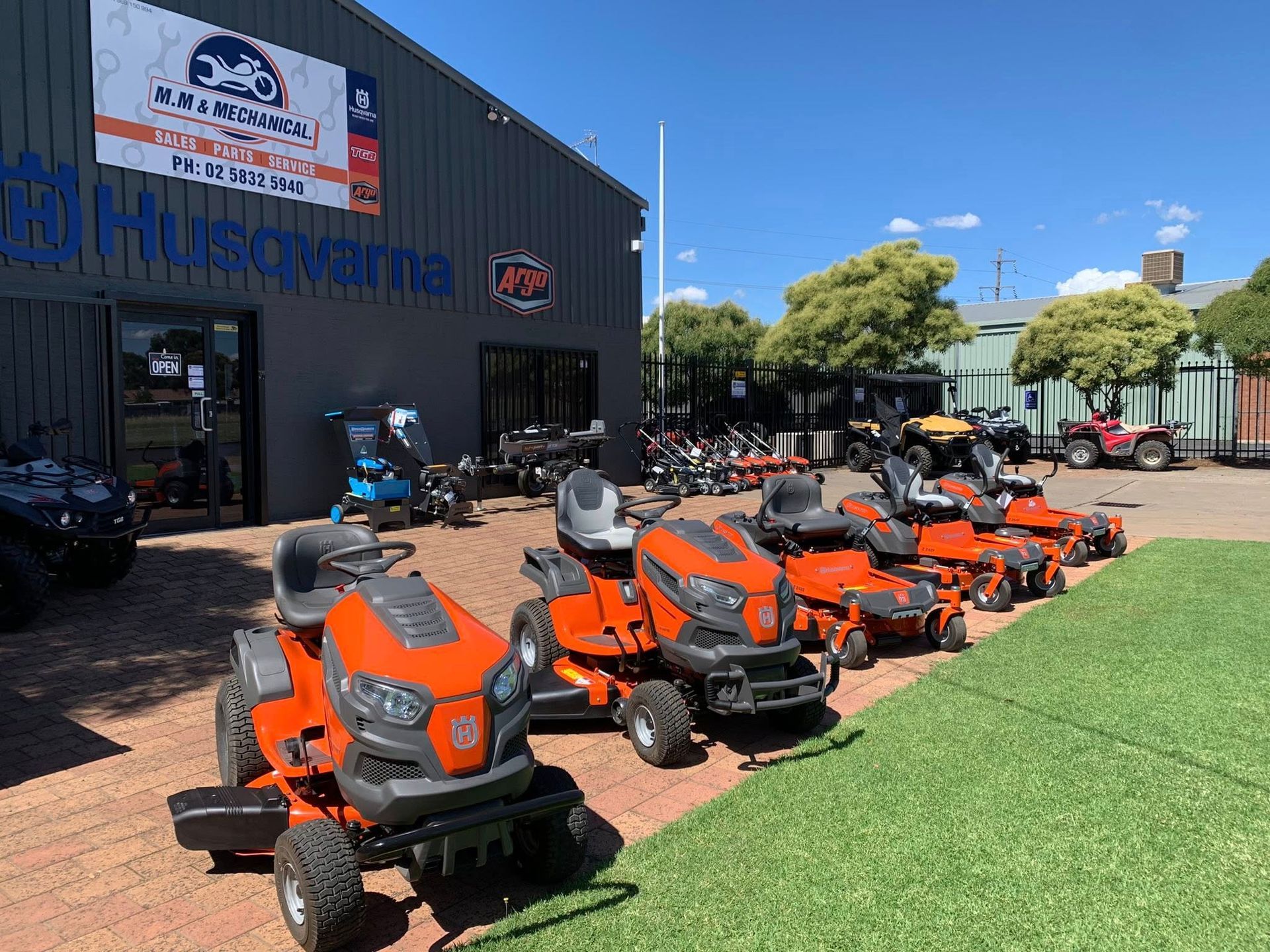 A Line of Orange Riding Lawn Mowers in Front of a Husqvarna Store — M.M & Mechanical in Dubbo, NSW