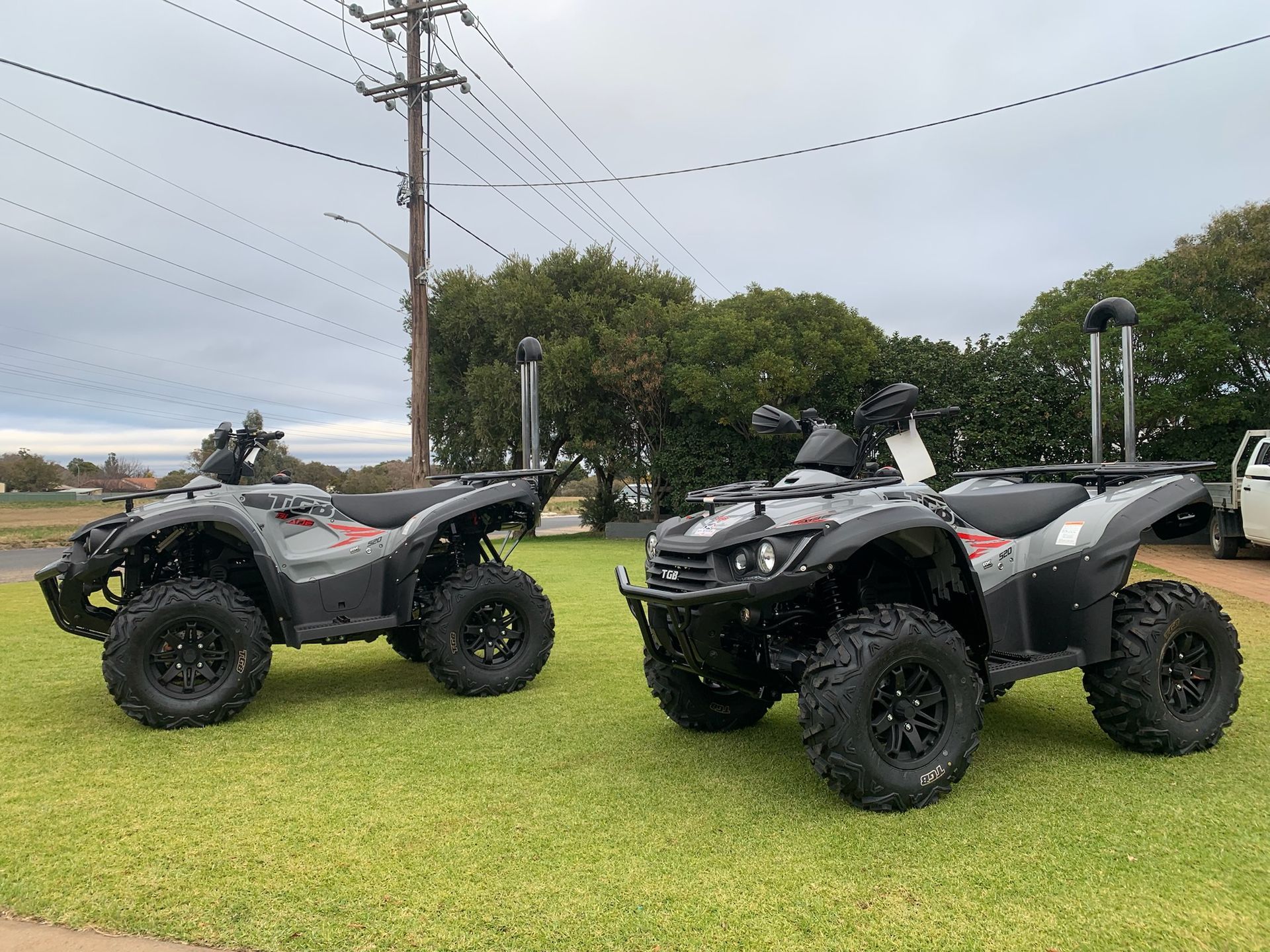 Two grey ATVs on grass in front of a building— M.M & Mechanical in Dubbo, NSW