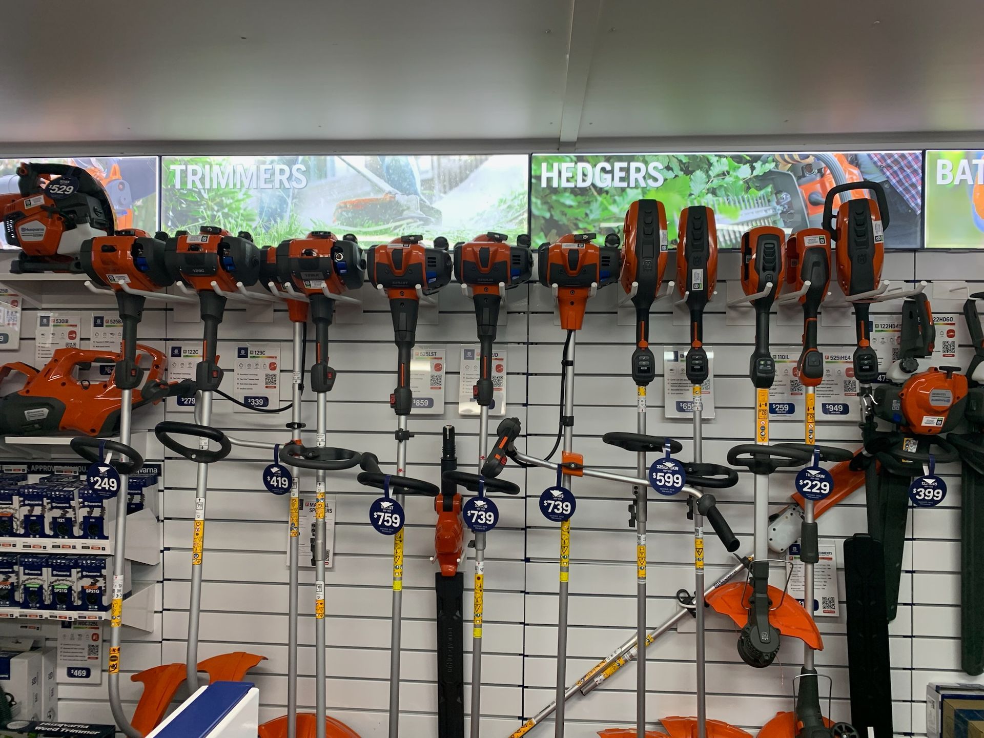 Inside a tool store, various gardening equipment is on display, with orange safety gear prominent— M.M & Mechanical in Dubbo, NSW