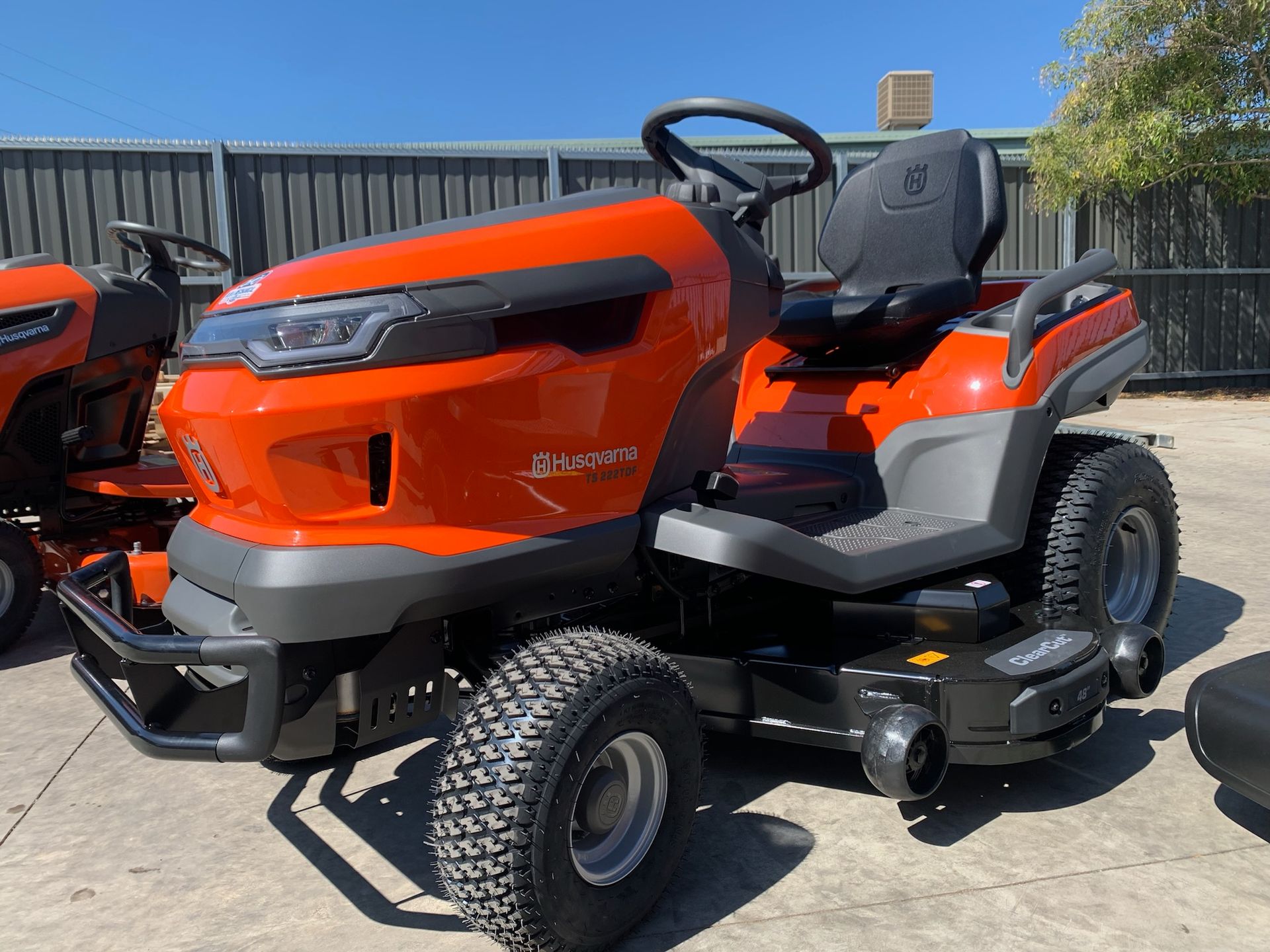 Orange and gray Husqvarna riding lawn mower on a concrete surface, angled view.— M.M & Mechanical in Dubbo, NSW