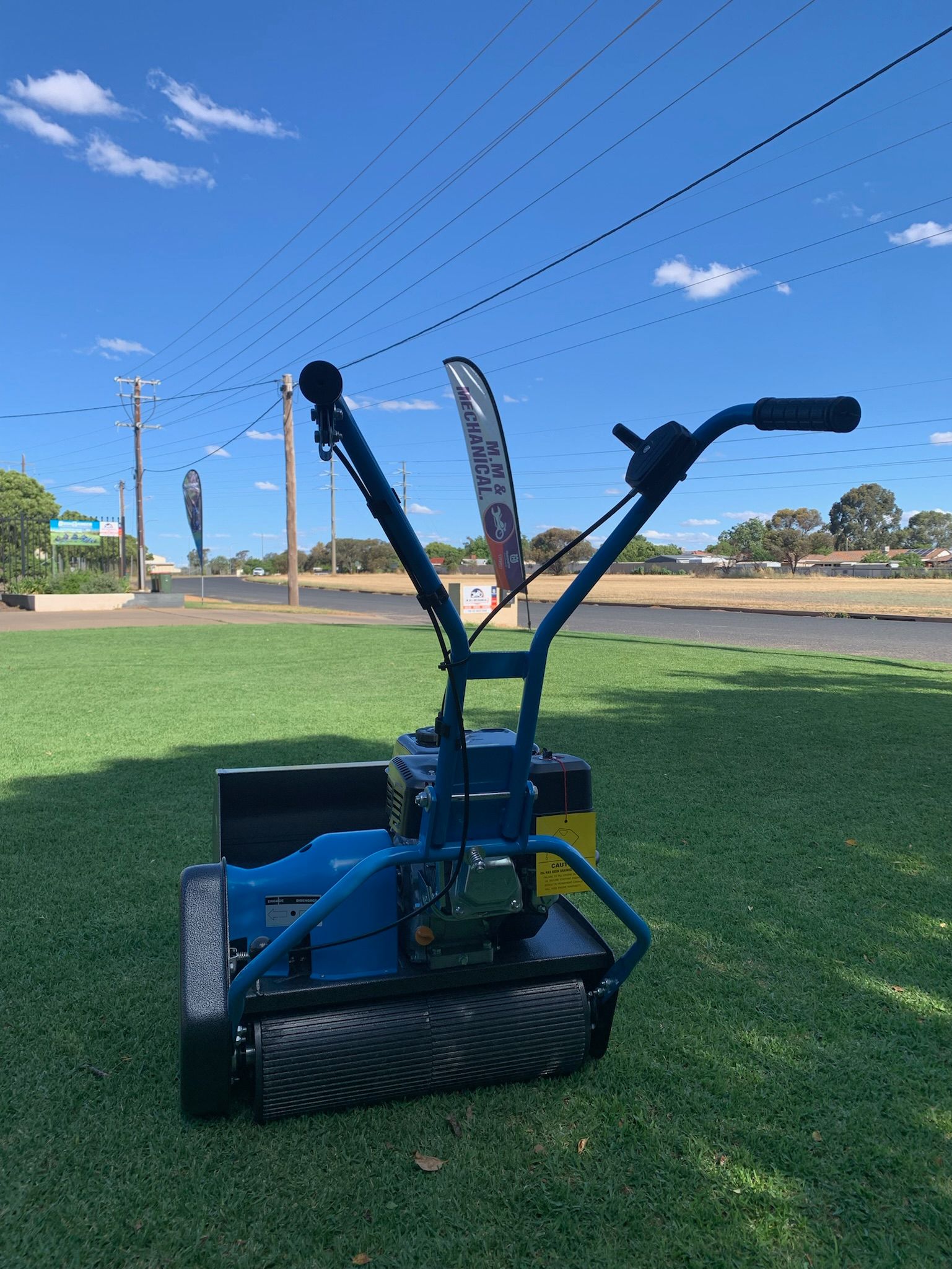Blue and Black Push Reel Mower in a Workshop Setting With a Motorcycle — M.M & Mechanical in Dubbo, NSW
