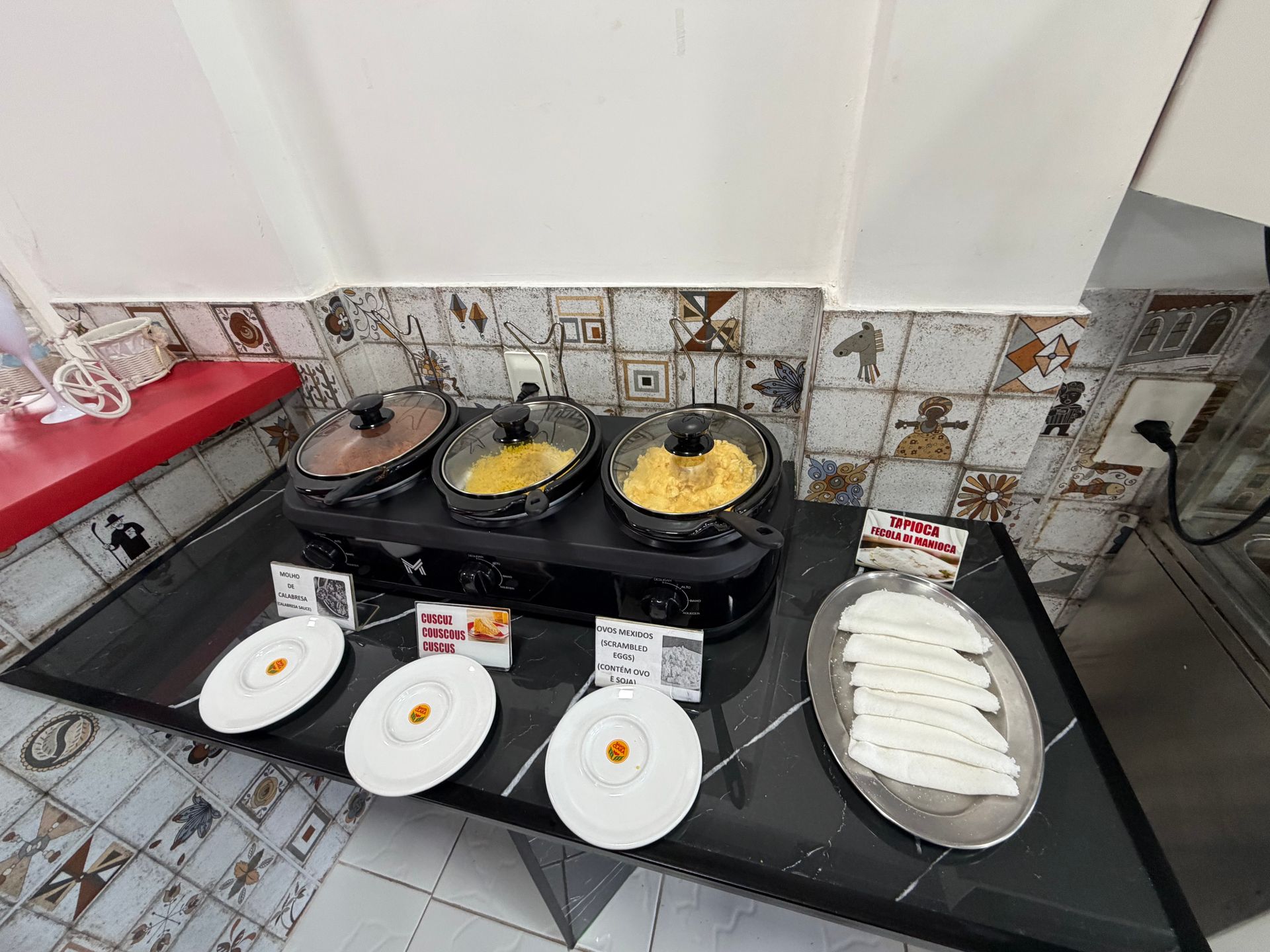 Balcão da cozinha com várias panelas e pratos com comida preparada, incluindo tortillas ou wraps enrolados.