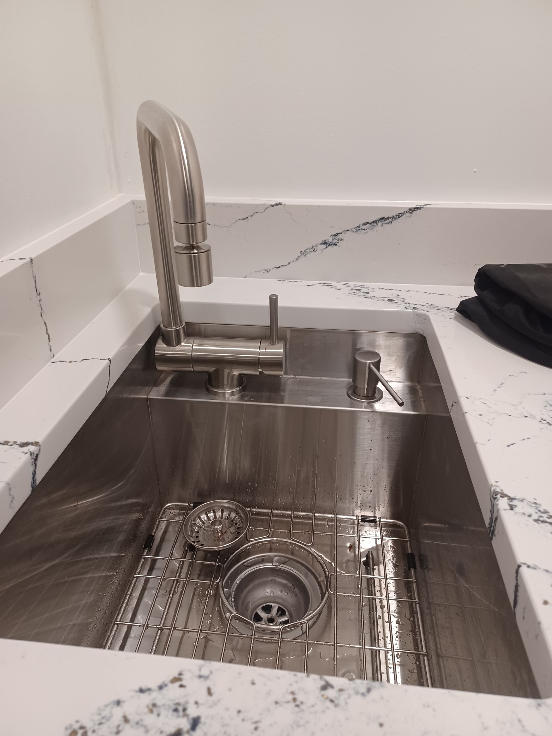 A stainless steel kitchen sink with a faucet on a counter.