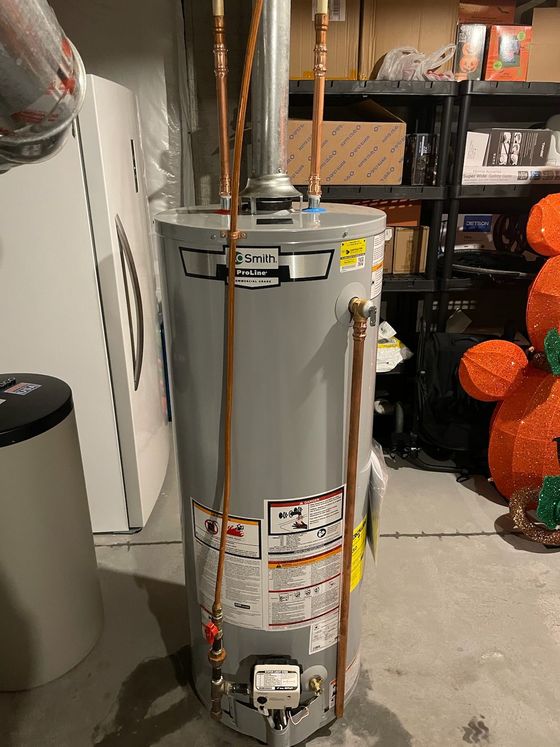 A water heater is sitting in a basement next to a washer and dryer.