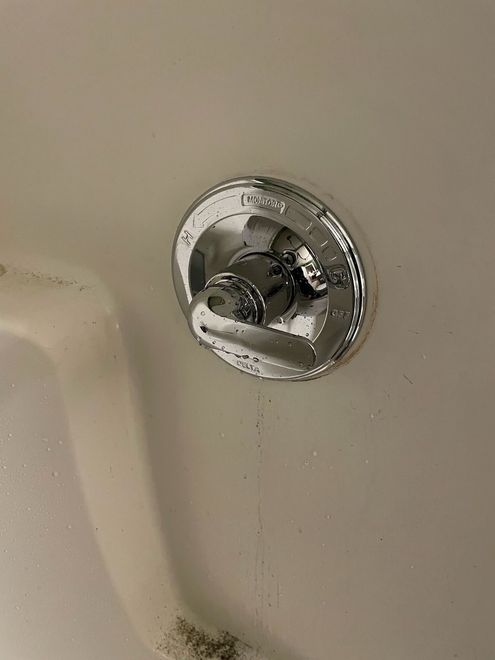 A close up of a shower valve on a wall.