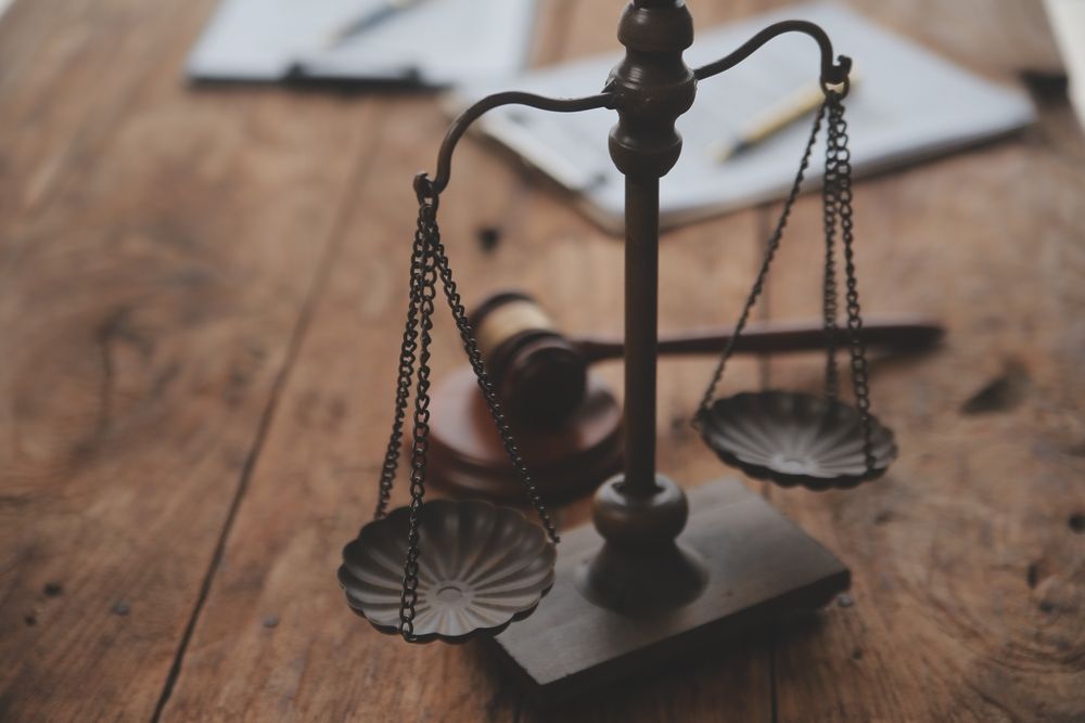 Scales of justice with a gavel and papers on a wooden desk.