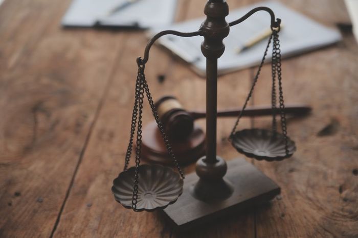 Scales of justice with a gavel and papers on a wooden desk.
