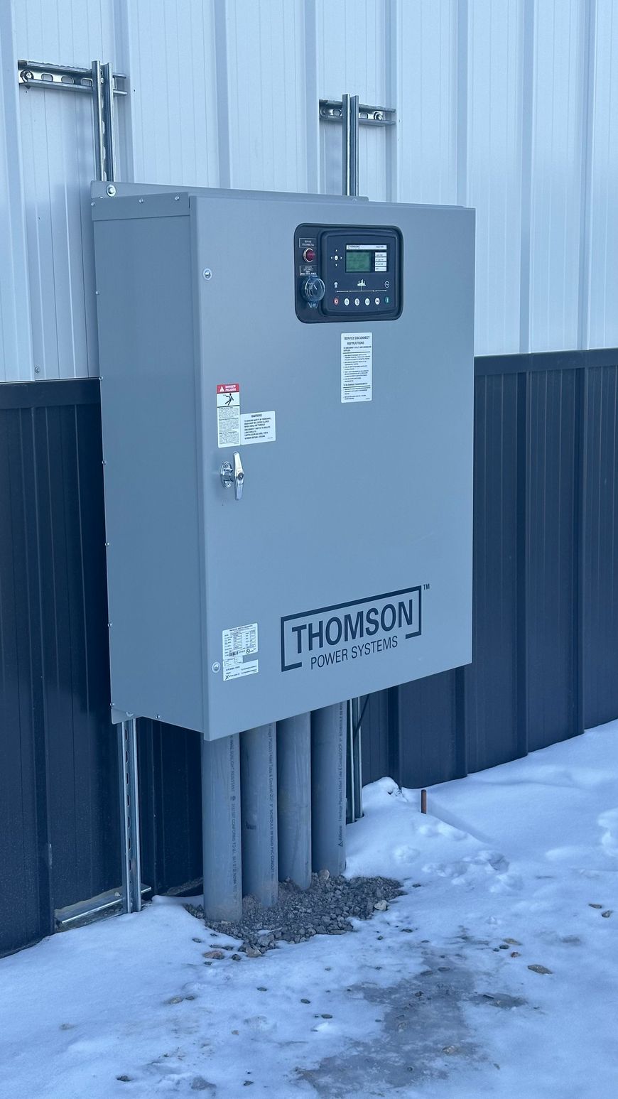 A large electrical box is attached to the side of a building.