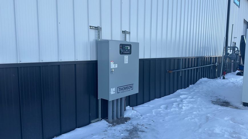 A large electrical box is attached to the side of a building.