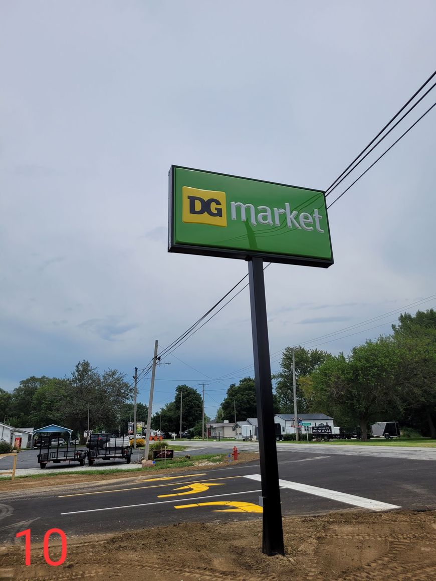 A green sign that says dg market is sitting on the side of a road.