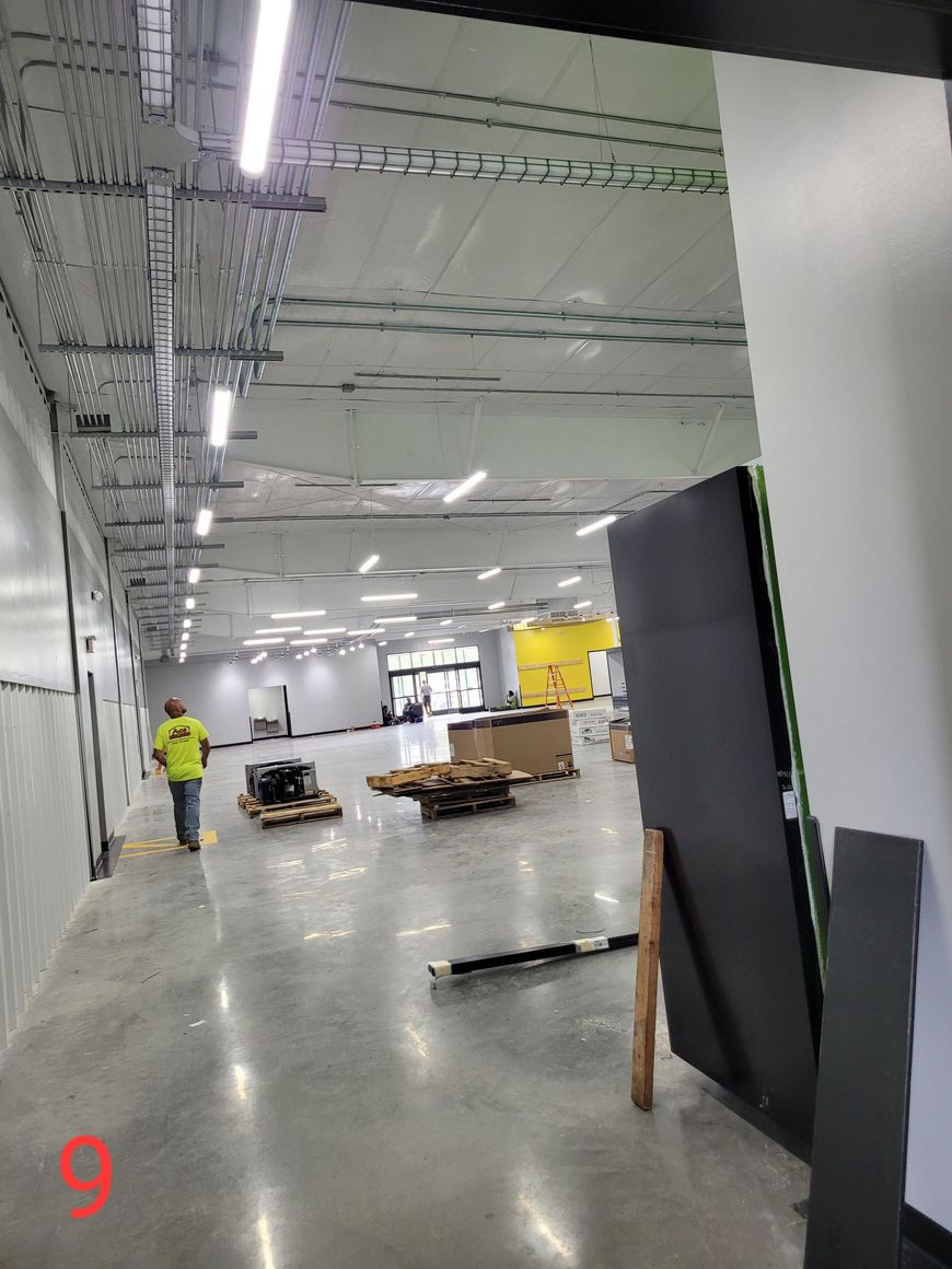 A man in a yellow vest is walking through a large room.