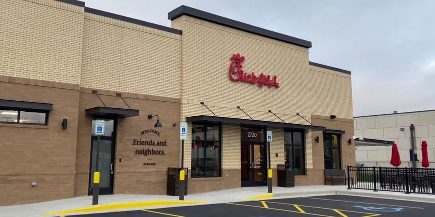 A chick fil a restaurant with a parking lot in front of it.