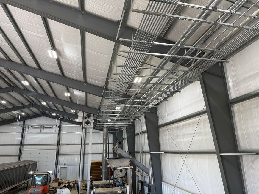 A large warehouse with a lot of pipes hanging from the ceiling.