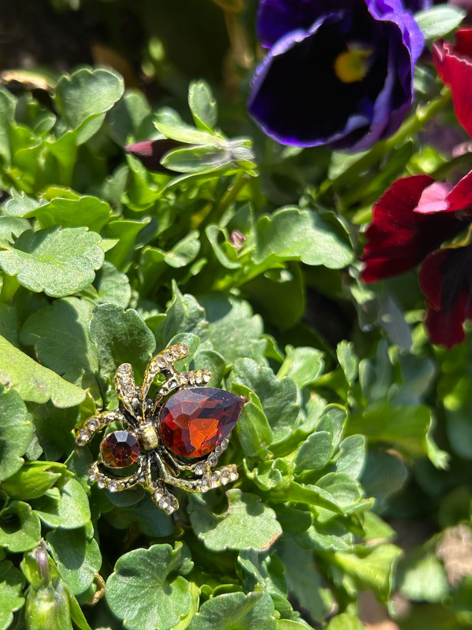 A brooch in the shape of a spider is sitting on top of a plant.