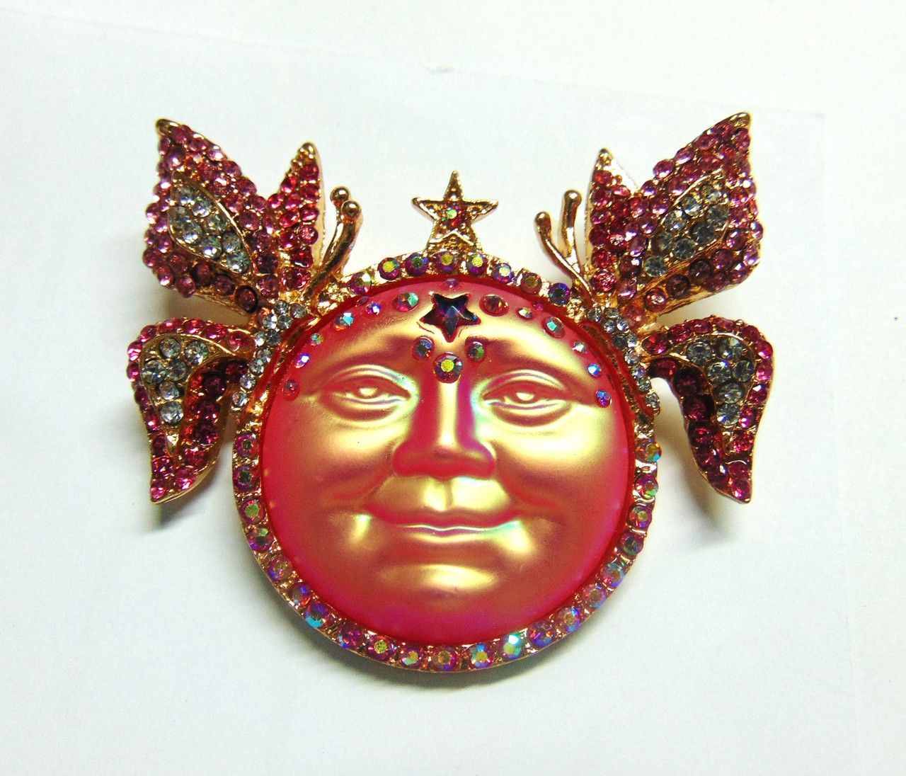 A brooch with a face on it is on a rock