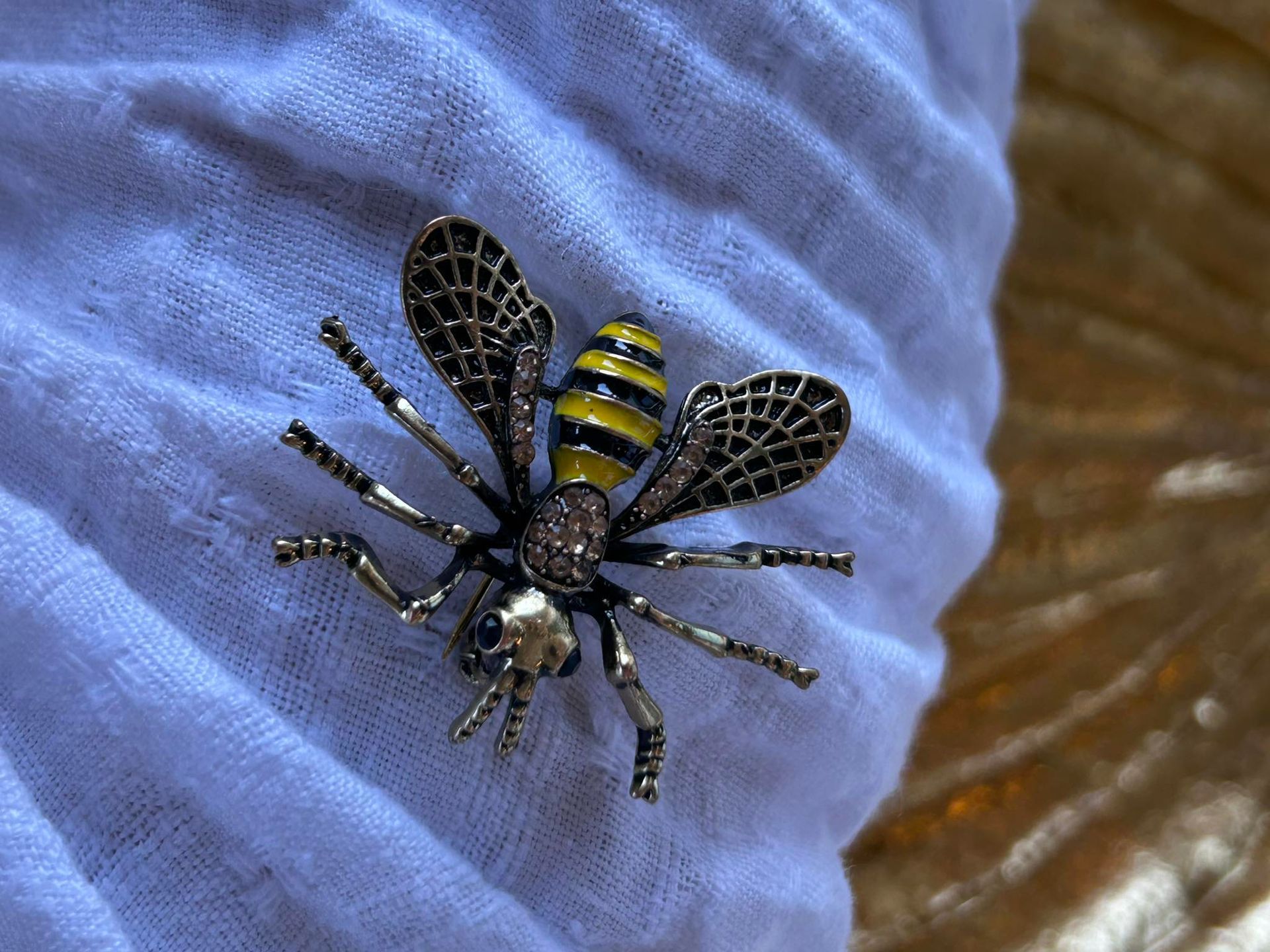 A person is holding a bee brooch on their finger.