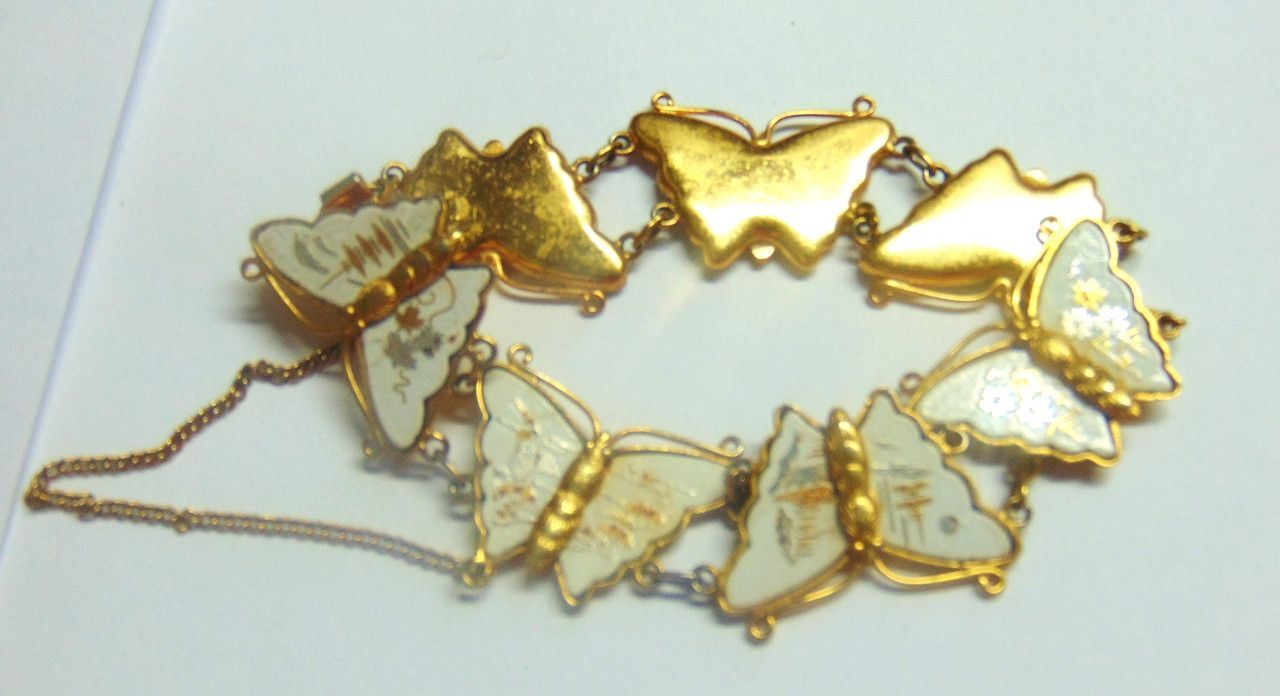 A person is holding a bracelet with white butterflies on it