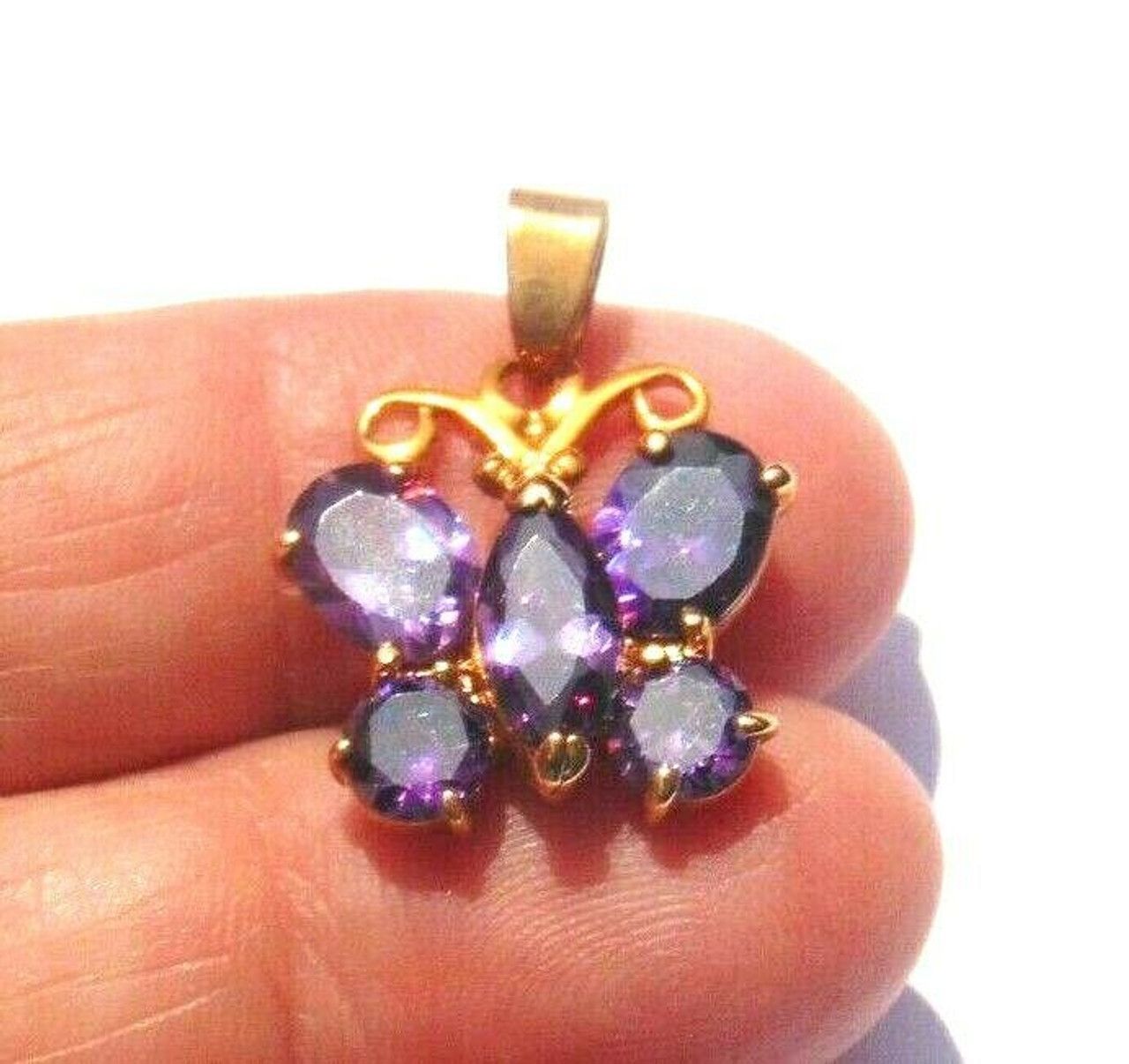A gold butterfly shaped pendant with purple stones