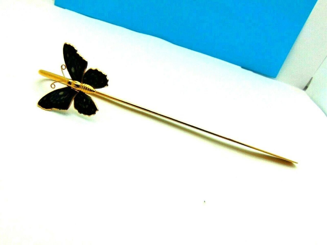 A person is holding a gold stick with a butterfly on it