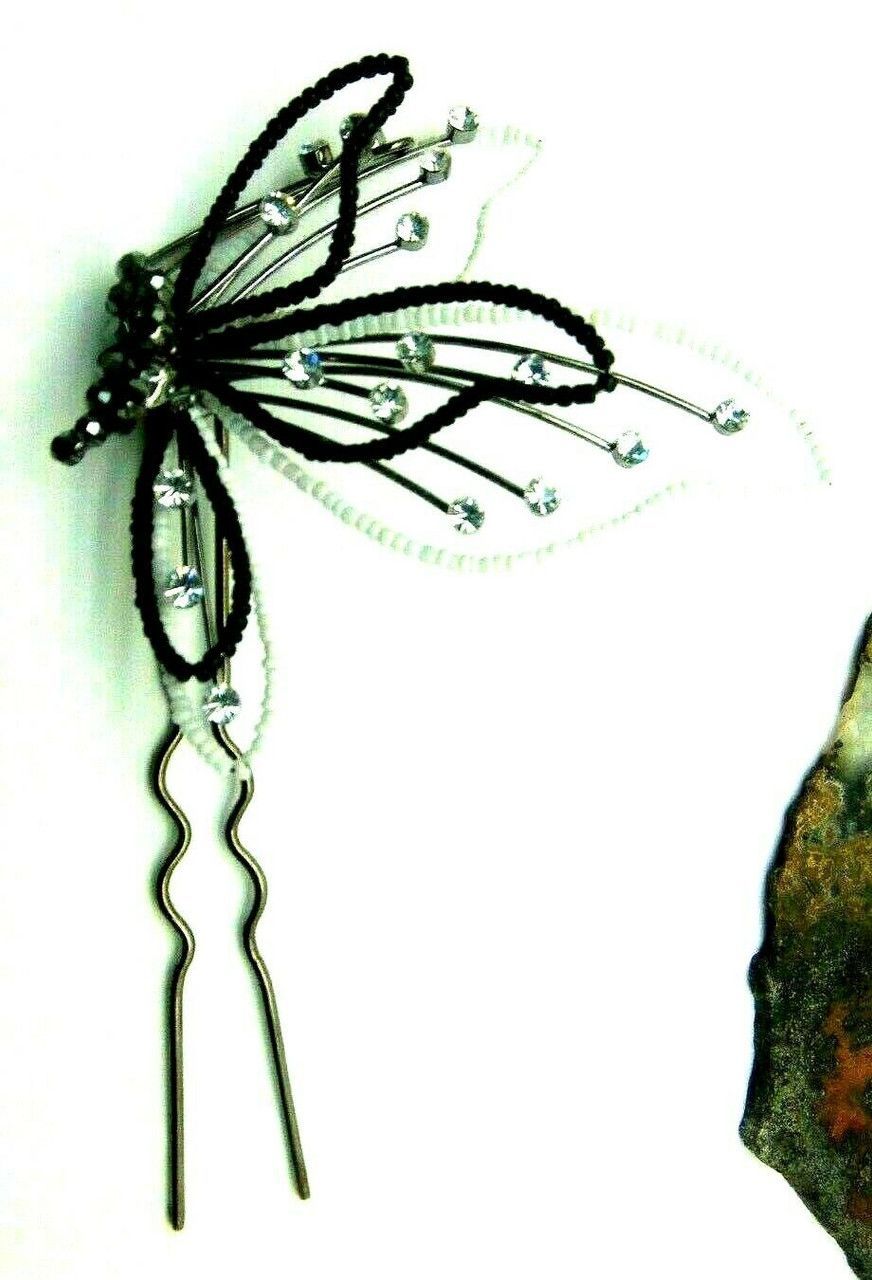 A hand is holding a black and white butterfly hair pin