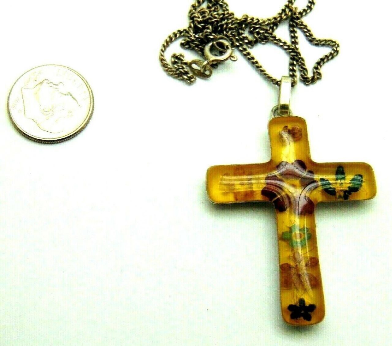 A person is holding a yellow cross with flowers on it