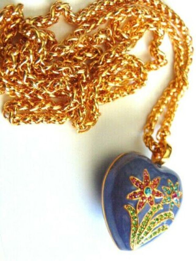 A person is holding a heart shaped pendant with flowers on it