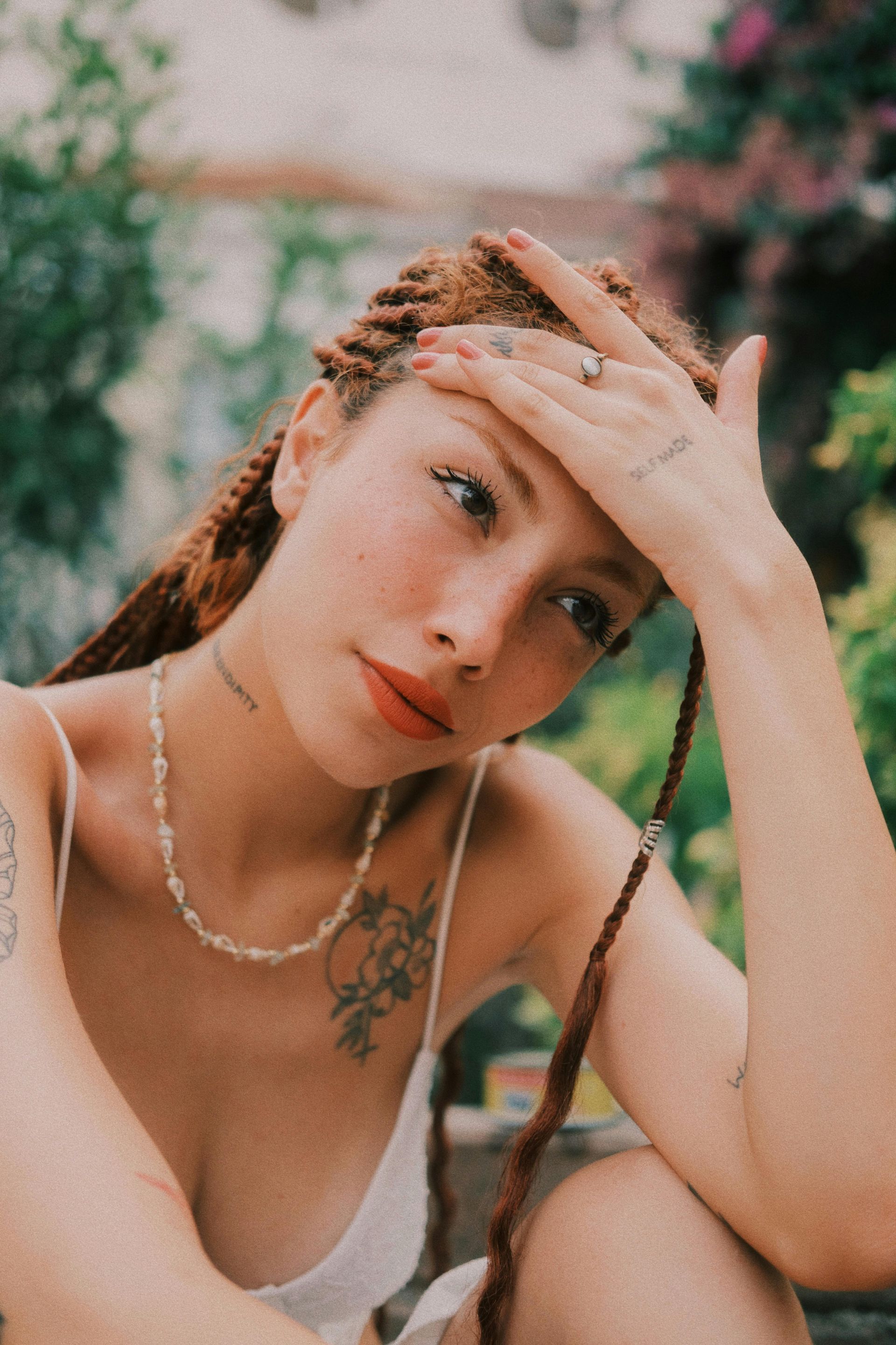 a woman with a necklace is holding her head