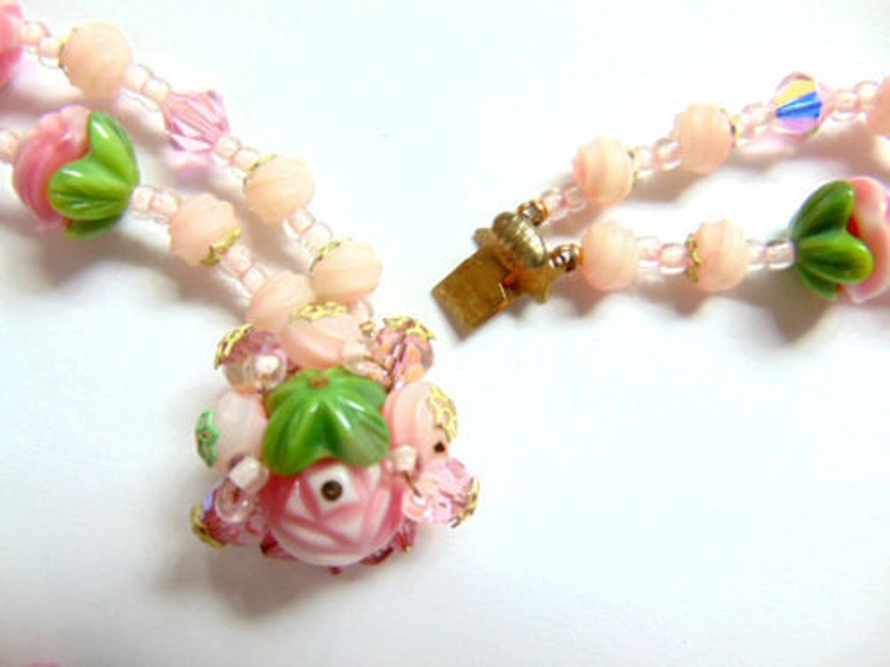 A necklace with pink and green beads on a white surface